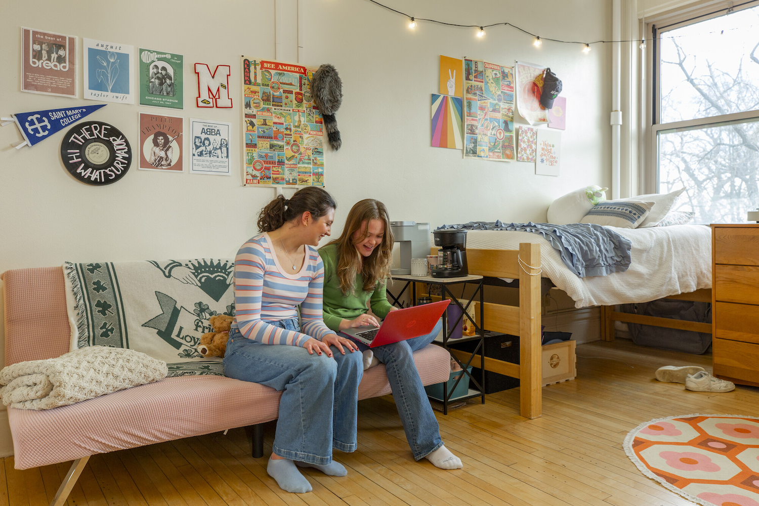 two Saint Mary's students sitting in a dorm talking and looking at a computer