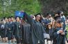 Alumna displaying diploma while in commencement line